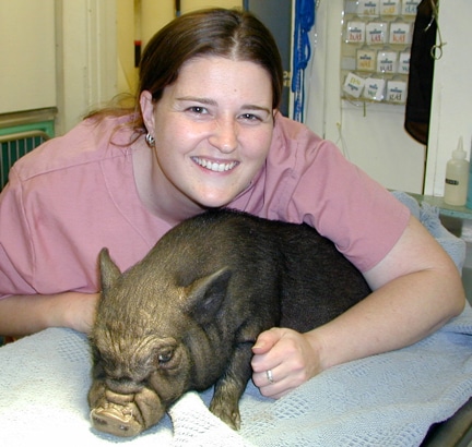 Cassandra smiling with pig on table.